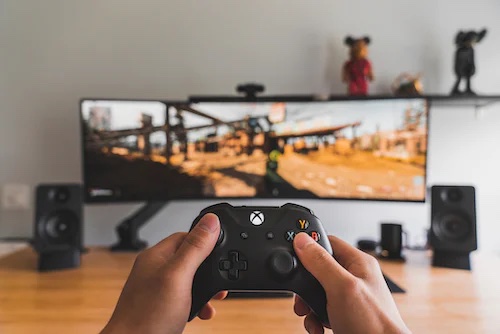 Hands holding a video game controller and playing a game on a TV